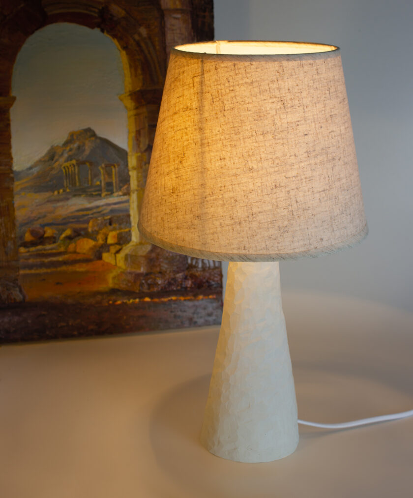 Classic table lamp with beige shade. The base of the lamp is made of ceramic by hand-molding. A beautiful addition to your bedroom bedside table. The small size of the textured lampshade makes it better to place this lamp even in a distant space. The textile lampshade has a dense fabric and backing, so the lampshade does not change color when turned on and does not scatter light through the fabric, so the lamp is perfect for reading books before bed. The cone-shaped matte ceramic stand has many carved edges and beautifully refracts the light emanating from the lampshade. Thus, the lamp attracts the appearance of a unique piece of art, which will undoubtedly emphasize the refined taste of its owner. The lamp has gold fittings that blend seamlessly with natural white ceramics.